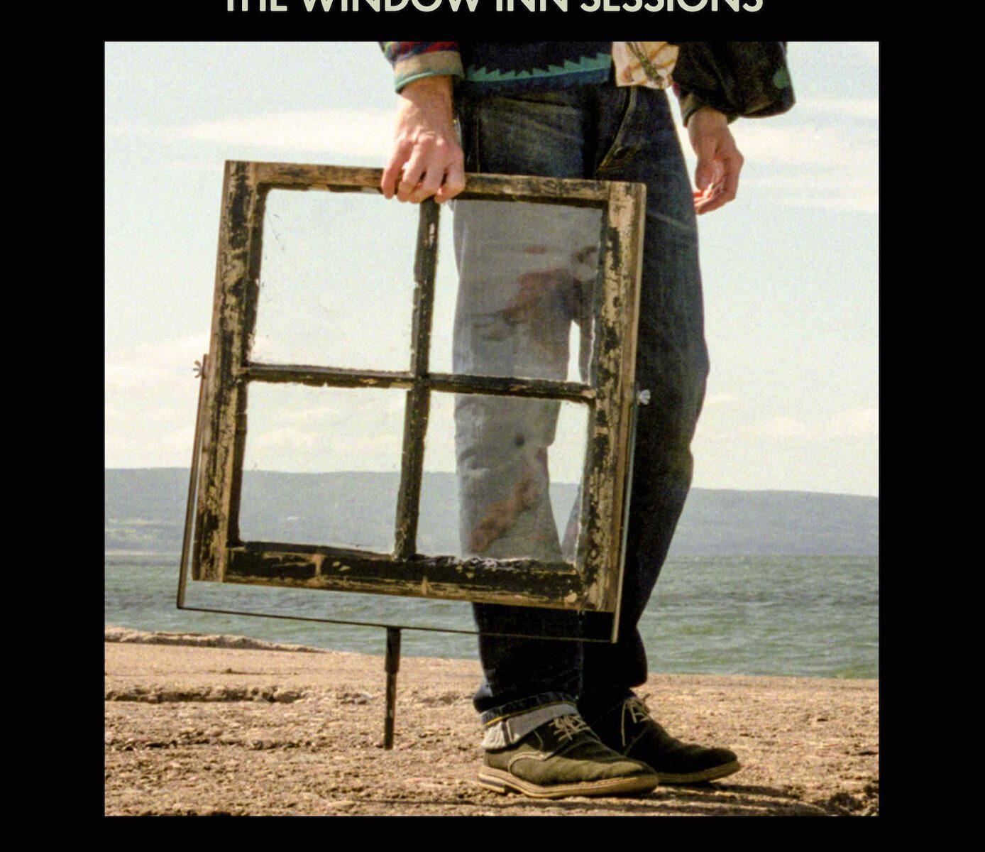 The Window Inn Sessions cover for Joel Plaskett featuring a man holding a square old-fashioned window down by his side